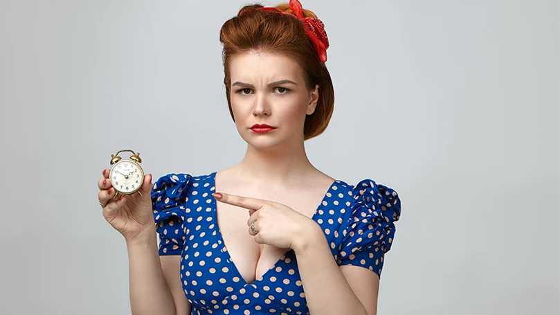An image of a woman holding an alarm clock.