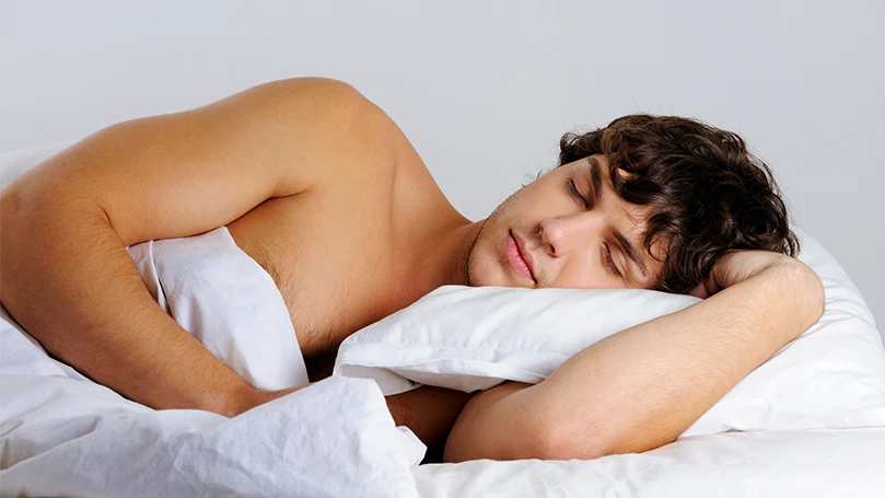 An image of a young man sleeping on his side.