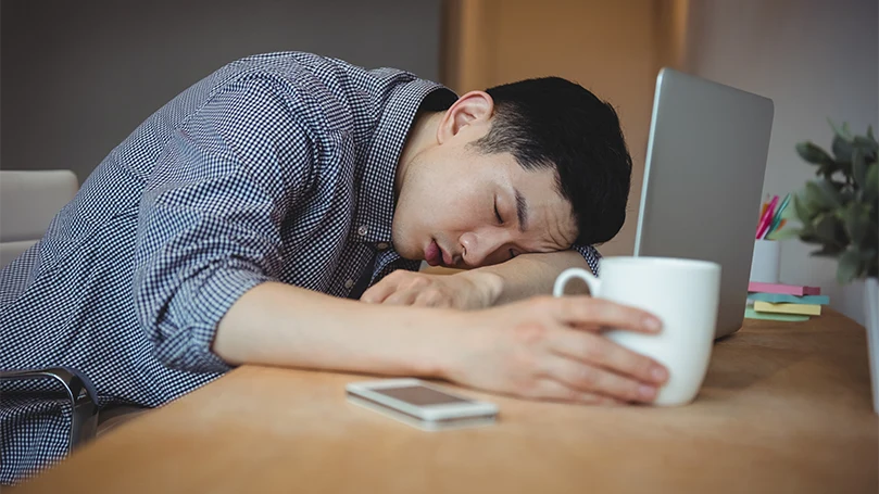 An image of a man fallen asleep in his office.