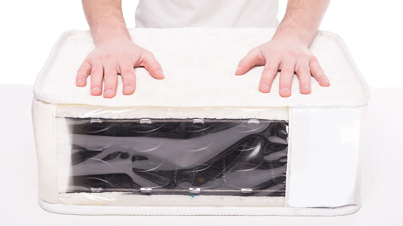 an image of a man pressing a new mattress gently