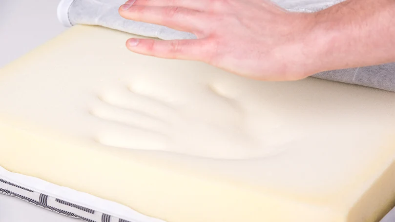 an image of a man pressing with hands memory foam mattress