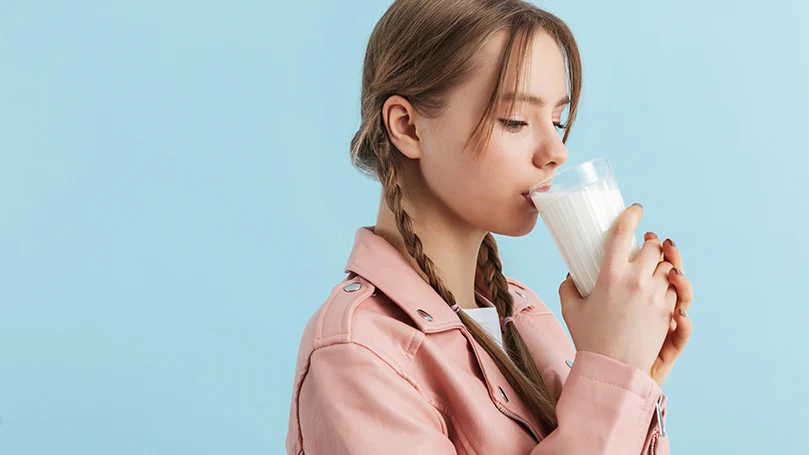 An image of a young woman drinking a glass of milk.
