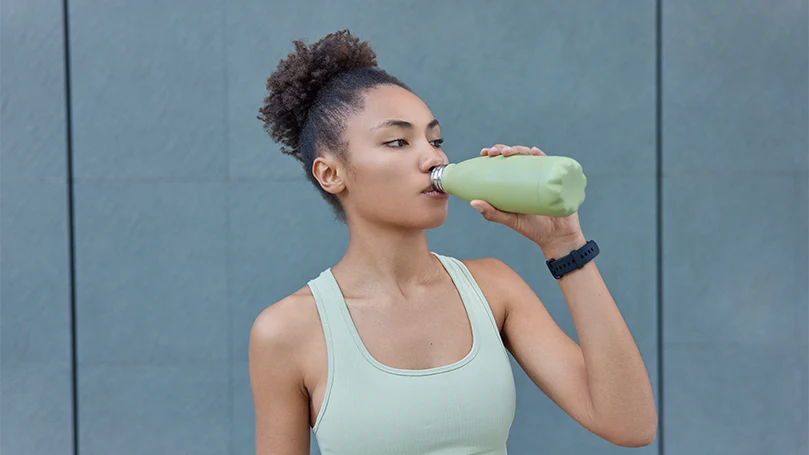An image of a young woman drinking water during the workout.