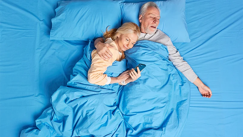 An image of an older couple in bed sleeping well without snoring issues.