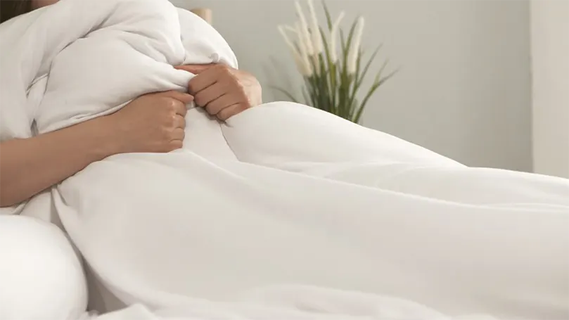 An image of A man covered with Slumberdown Climate Control duvet .