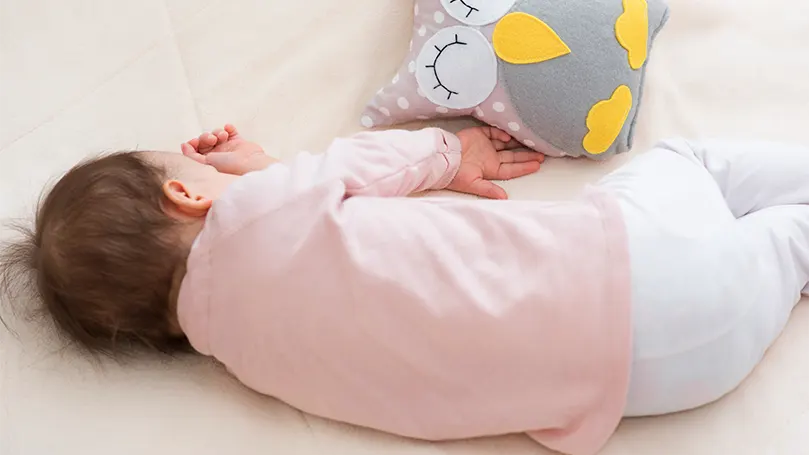 An image of a baby sleeping on side.