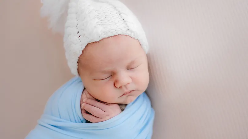 An image of a baby wearing a hat while sleeping.