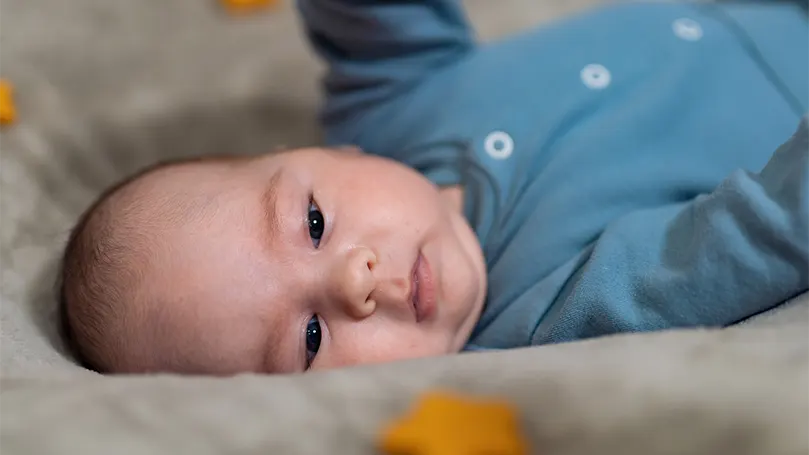 An image of a newborn boy laying on side.