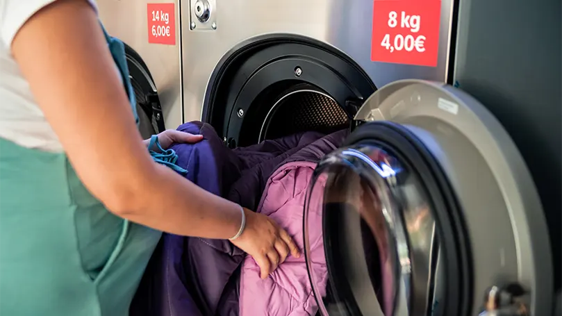 An image of a pregnant woman putting blankets in a washing machine.