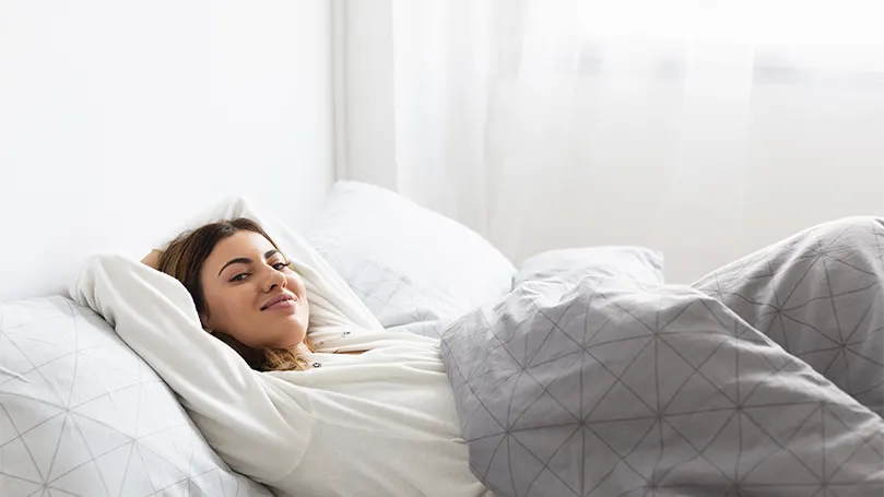 An image of a relaxed woman in bed.