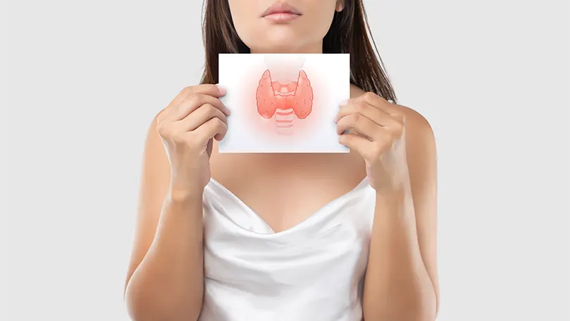 An image of a woman holding a paper depicting hypothyroidism.
