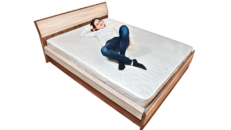 An image of a woman laying on a bed with mattress.