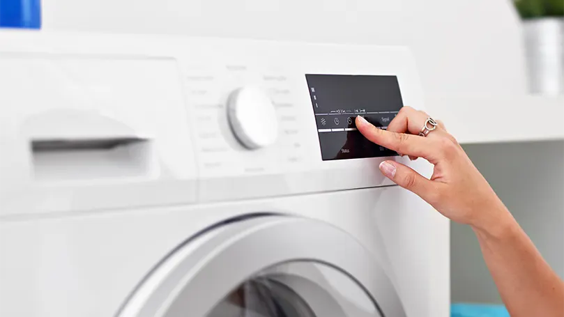 An image of a woman setting up the low dry on washing machine.
