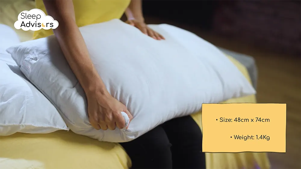 our reviewer squeezing a Slumberdown Super Support pillow with its size and weight shown in bottom right corner