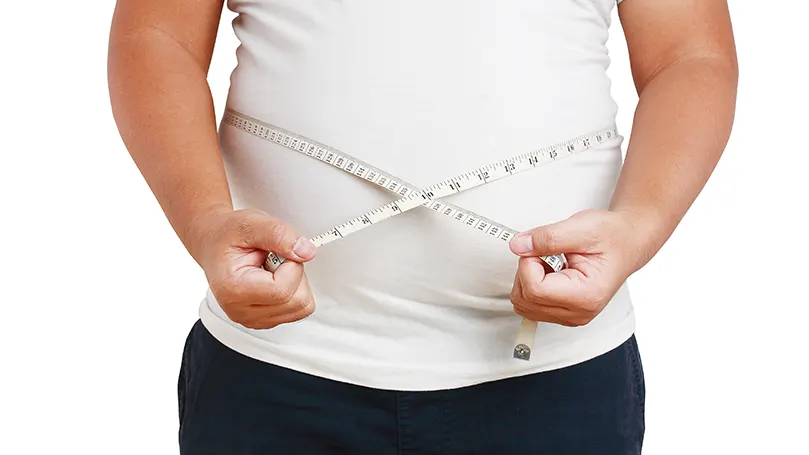 An image of a fat man measures his belly with a tape measure.
