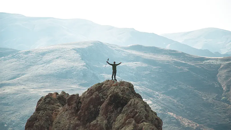 An image of a hiker on top of a mountain.