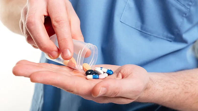 An image of a male doctor holding antibiotics in hand.