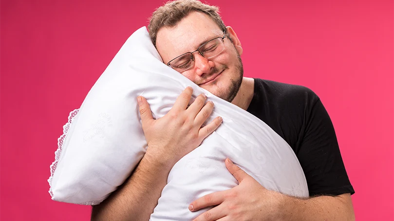 An image of a man hugging a breathing pillow.