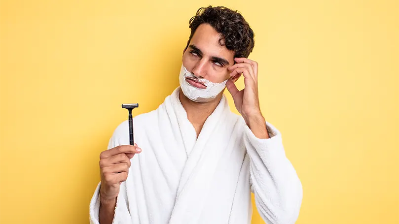 An image of a man putting a shaving foam on his face.