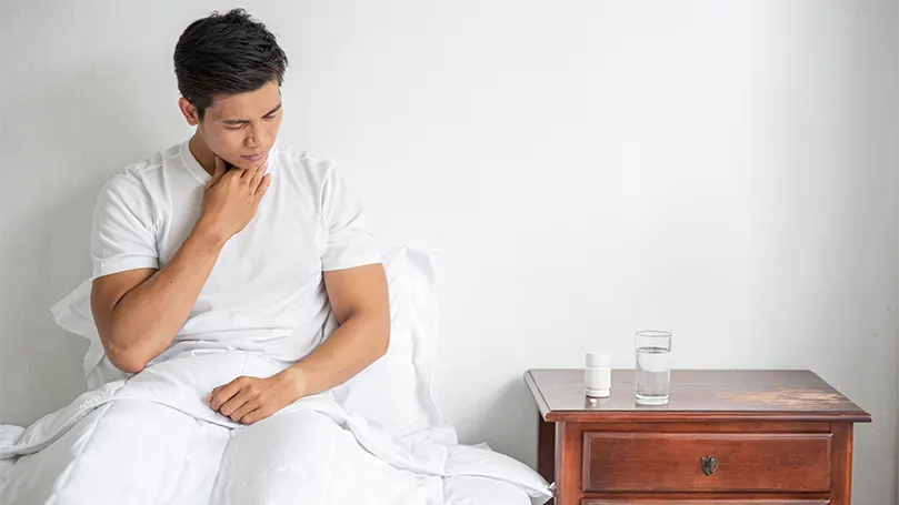 A man in bed suffering from gastroesophageal reflux disease.