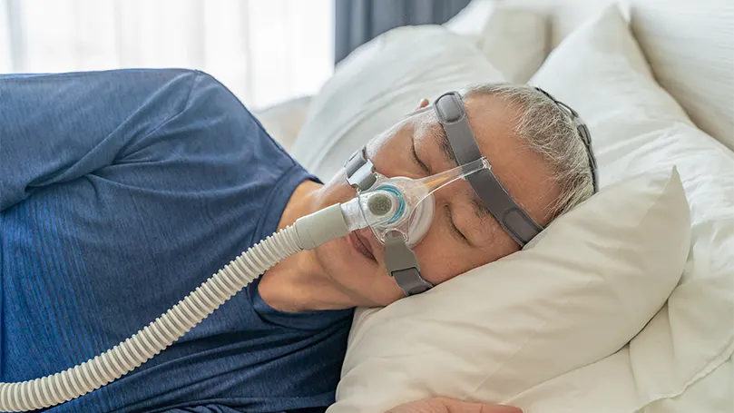 An older man sleeping with CPAP mask