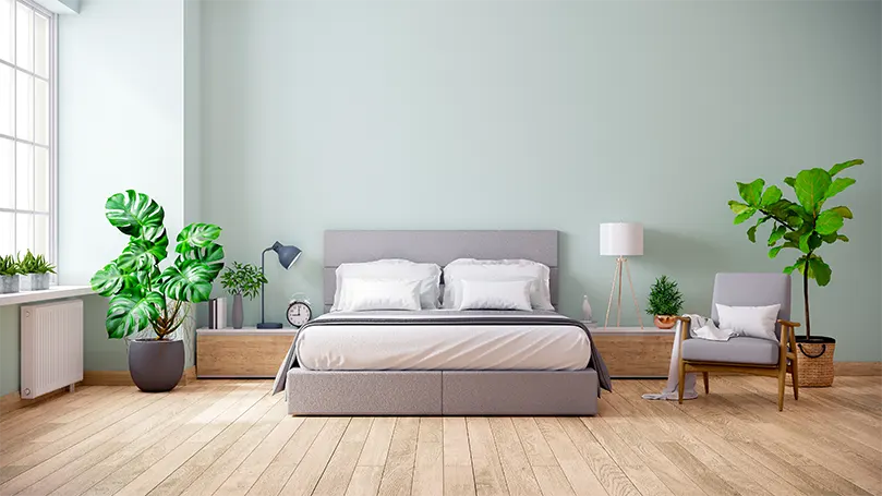 An image of a modern bedroom with plants in corners.