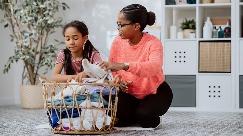 An image of a mom and daughter preparing pajamas and clothes for washing.