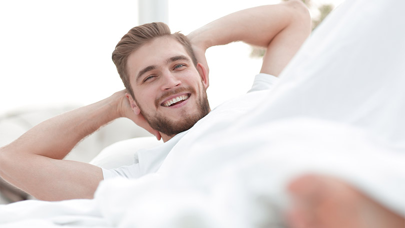 An image of a satisfied man in a bed.