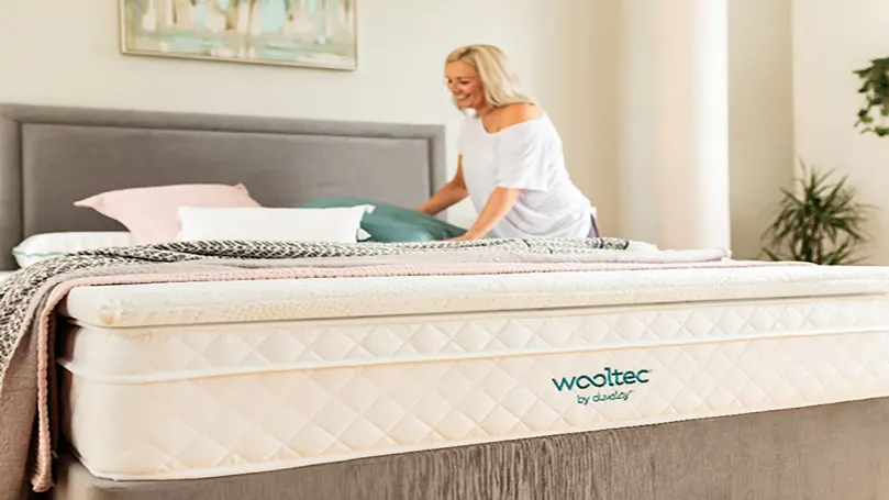 An image of a woman putting her Duvalay mattress topper on a mattress.