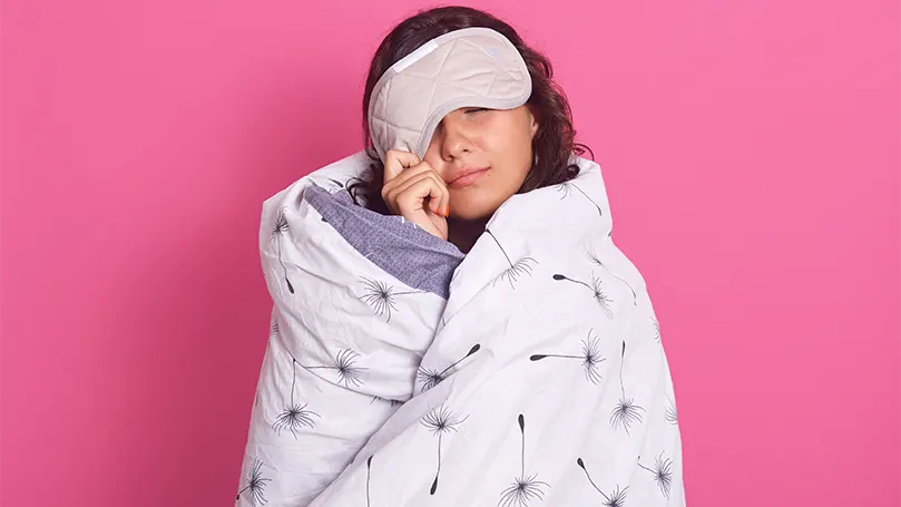 An image of a woman wrapped in a blanket suffering from sleep inertia.