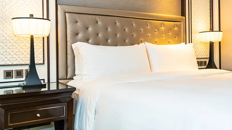 An image of a wooden night table beside bed.