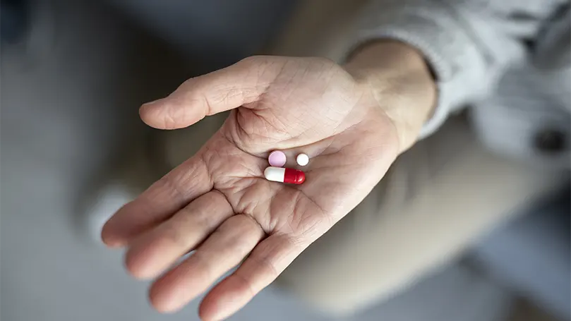 An image of an older patient holding medicine for Parkinson's disease.