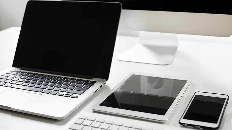 An image of laptop and smart phones on a desk.