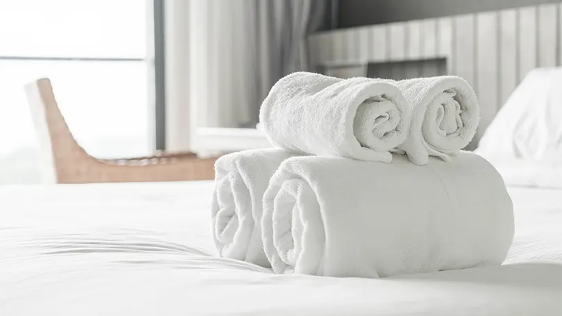An image of 2 white Egyptian cotton towels on bed.