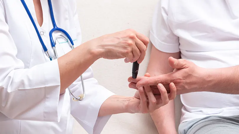 An image of a doctor is checking a patient's blood sugar level.