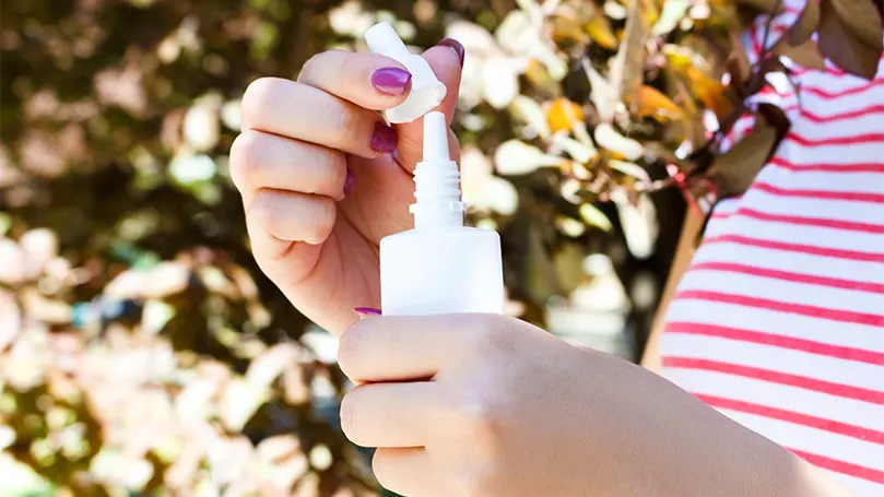 An image of a female holding a nasal spray.