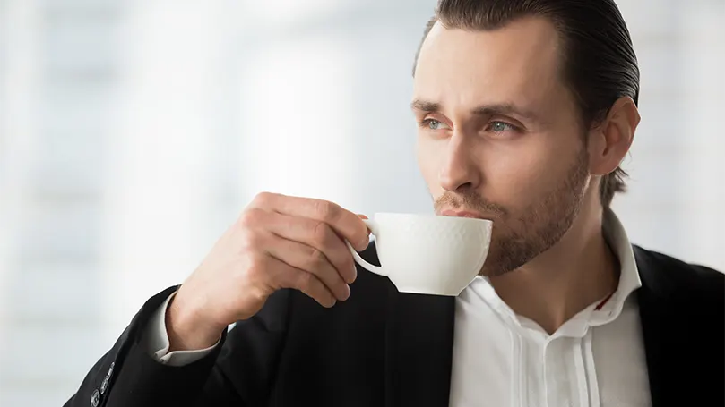 An image of a man drinking coffee and daydreaming.