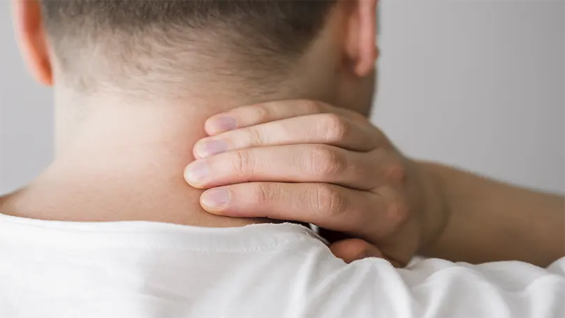 An image of a man holding his neck due to neck pain.
