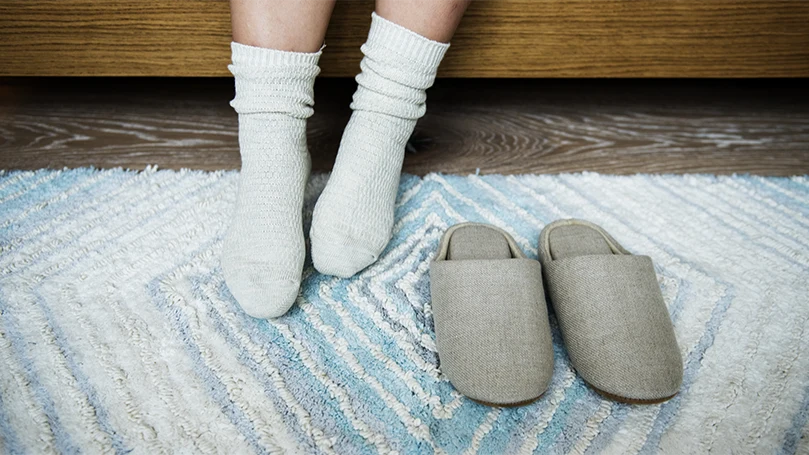 An image of a person waking up and standing on a bedroom rug.