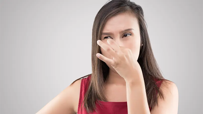 An image of a woman holding her nose due to an unpleasant musty smell.