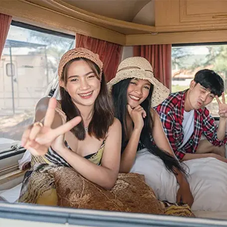 A couple of friends posing on a caravan mattress in an RV