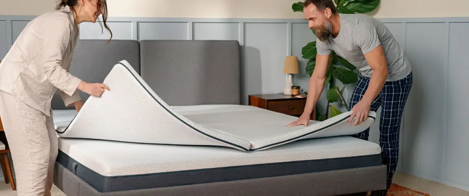 Couple placing Emma Flip Topper on bed