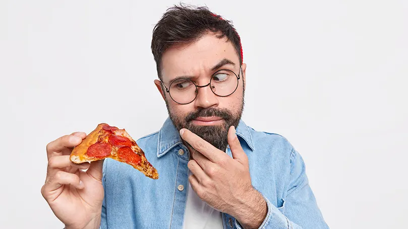a-bearded-man-holding-a-slice-of-pizza