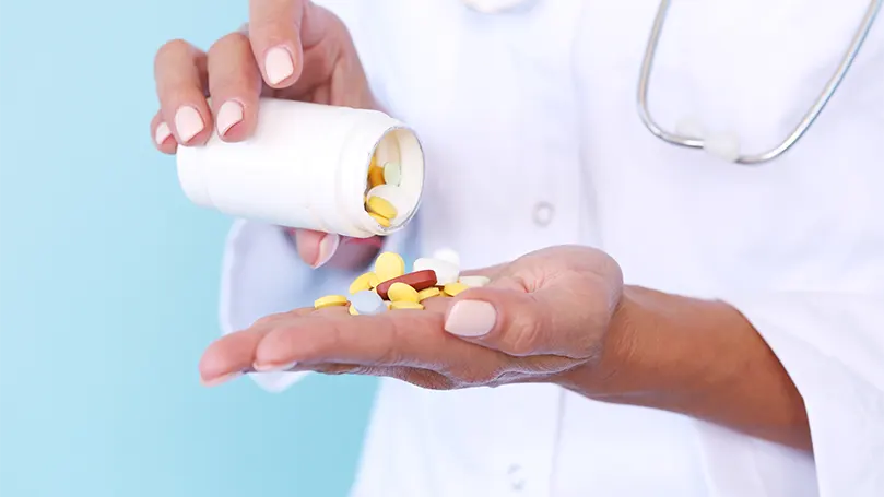A doctor taking out pills from a bottle.