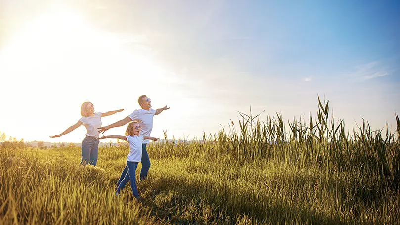 An image of a family outside running through a field