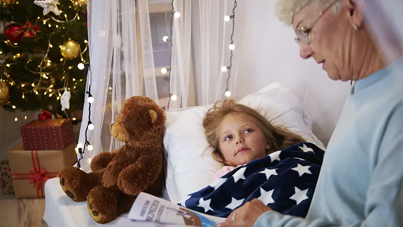 An image of a grandmom reading a book to her grandchild before sleep.