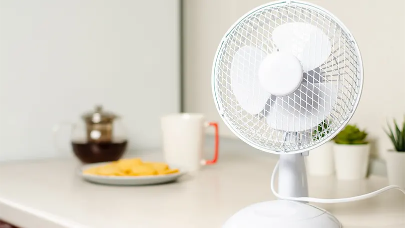 An image of a small rotating fan in kitchen.