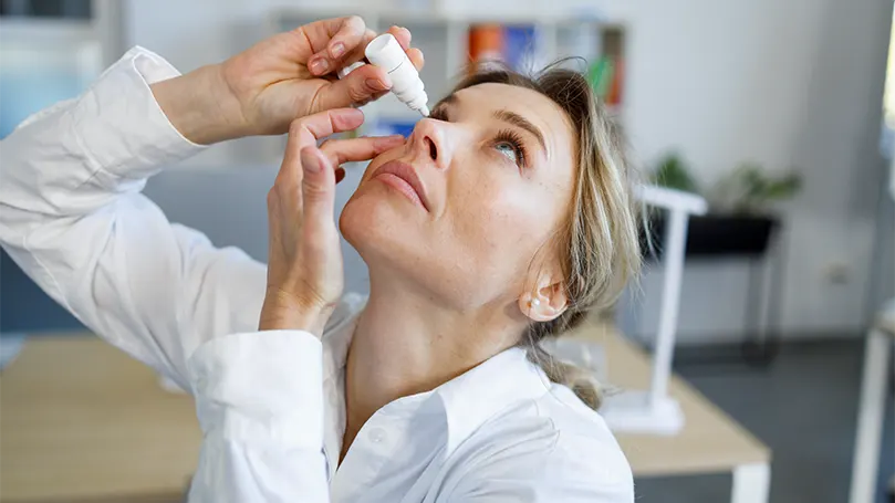 An image of a woman using eye drops