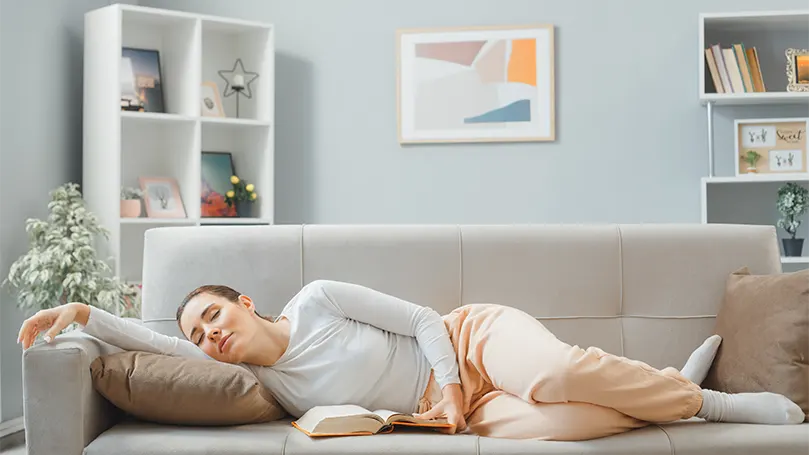 An image of a woman sleeping on side on a couch.