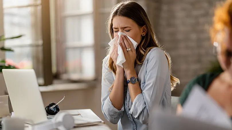 An image of a young businesswoman suffering from allergies.